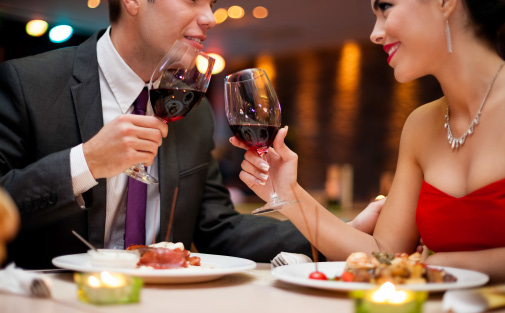A young couple toasting wine glasses at a fancy restaurant